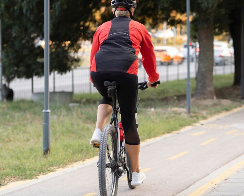 Vista posterior de la mujer mayor montando bicicleta al aire libre con espacio de copia