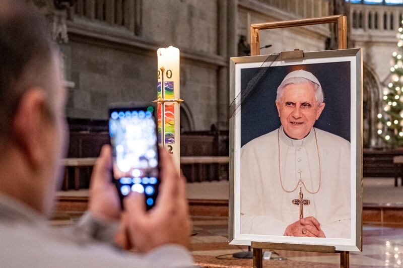 Una persona toma una foto de un retrato del Papa Emérito Benedicto XVI en la Catedral de San Pedro en Ratisbona, Alemania, el sábado 31 de diciembre de 2022. El papa emérito Benedicto XVI, el teólogo alemán que será recordado como el primer papa en 600 años en renunciar, ha muerto, anunció el Vaticano el sábado. Tenía 95 años (Armin Weigl/dpa via AP)