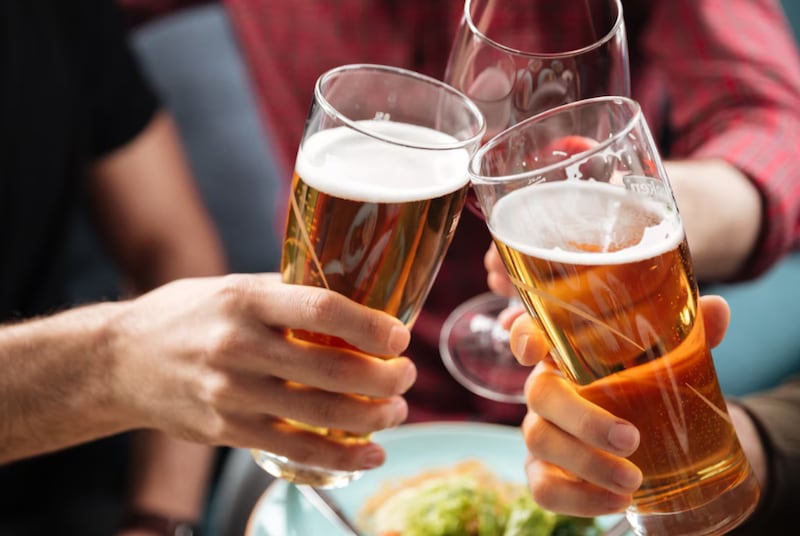 Jóvenes amigos sentados en la cafetería mientras bebe alcohol.