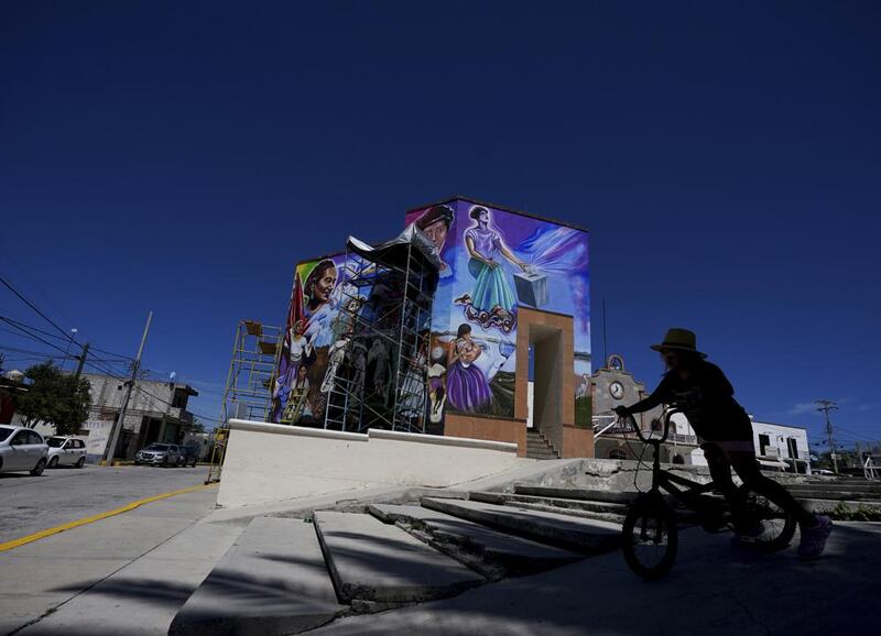 Una peatona monta su bicicleta frente a un mural pintado por el artista mexicano Jesús Rodríguez, en San Salvador, México, el sábado 30 de julio de 2022. Artistas que ayudan a revivir el muralismo o las imágenes visuales para compartir mensajes de importancia social y política, un movimiento que puso a México a la vanguardia del arte mundial hace un siglo. (Foto AP/Fernando Llano)