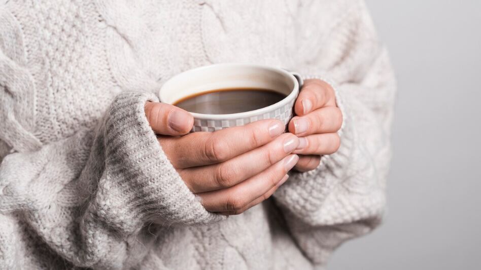 Sección media de mujer en ropa de lana con taza de café