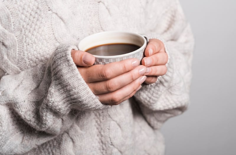 Sección media de mujer en ropa de lana con taza de café