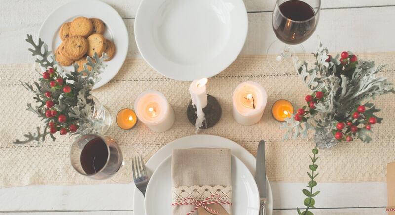 Mano de mujer irreconocible poniendo rama verde en la mesa de Navidad